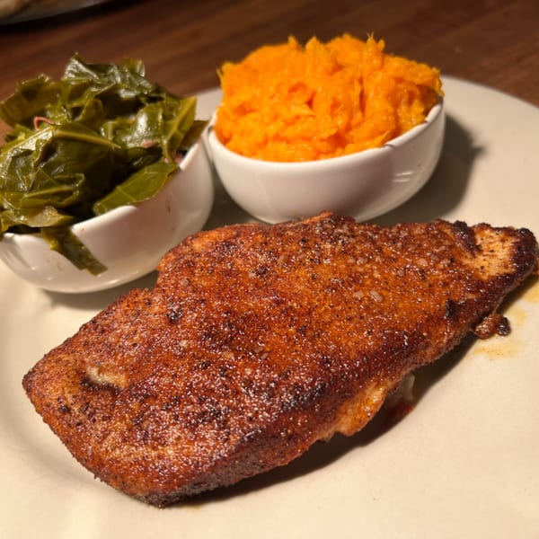 A plate of blackened fish with sides of collard greens and mashed sweet potatoes.