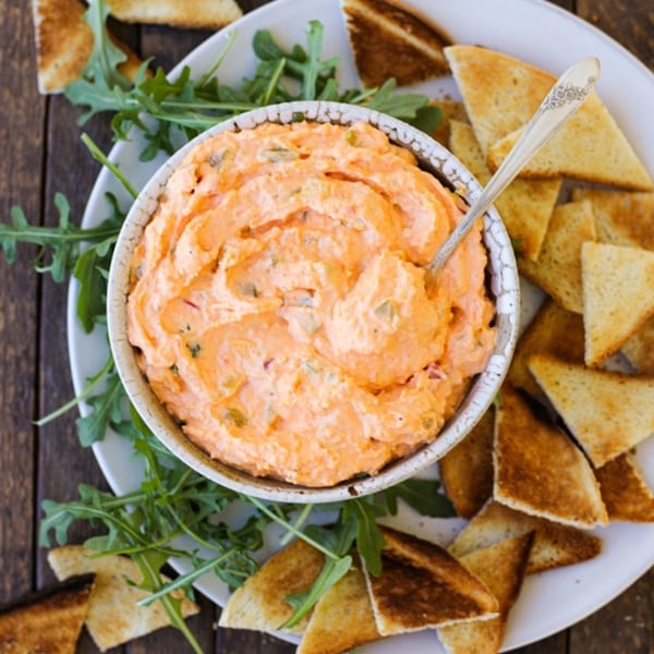 A bowl of Annie O's Kitchen's southern pimento cheese dip with toasted bread triangles and arugula.